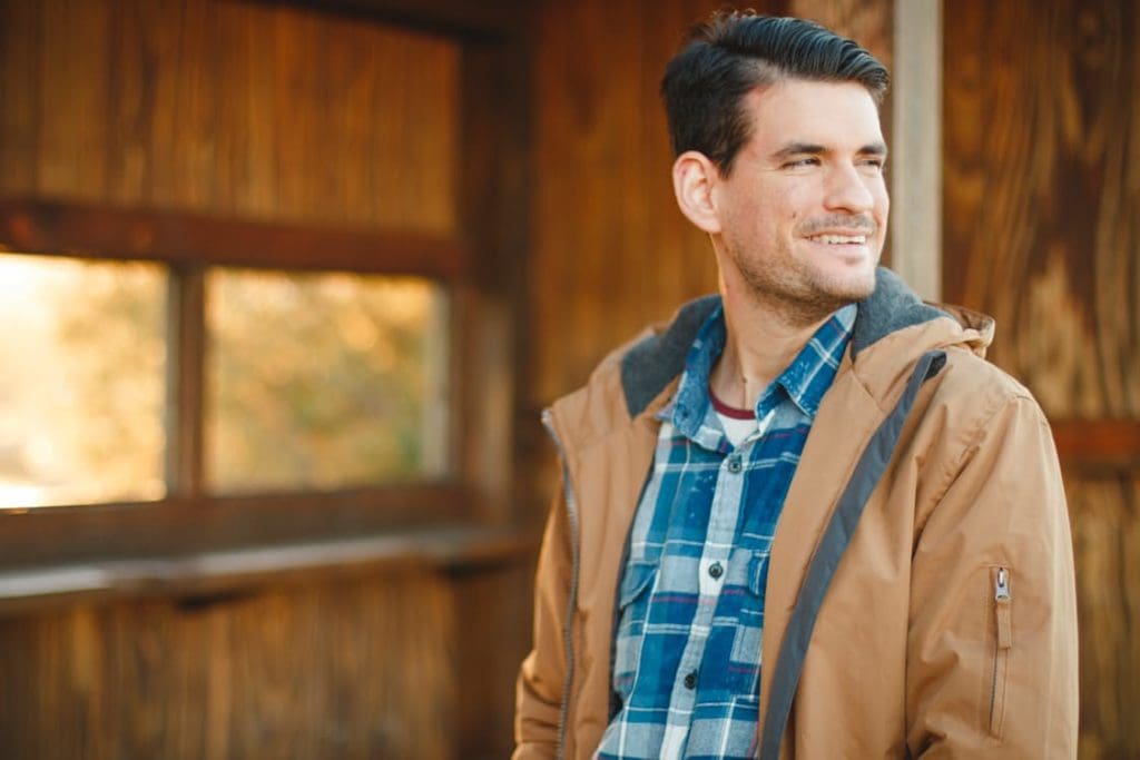 male in blue flannel and winter jacket smiling