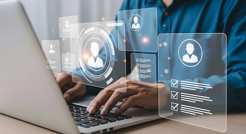 A person typing on a laptop with transparent digital profile icons and user interface elements floating above the keyboard, representing online user management or how to remove background check from digital profiles.