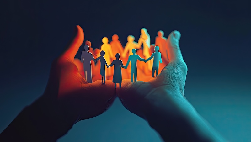 Two hands gently cup a group of glowing paper-cutout figures representing people of different genders, symbolizing community and unity. The image invites us to remove background check barriers, fostering genuine support and belonging for all.