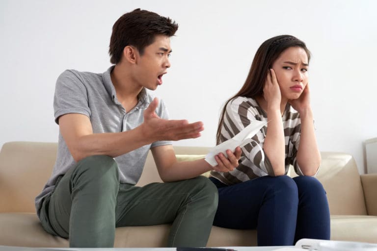 a man and woman are sitting on a couch and talking to each other.