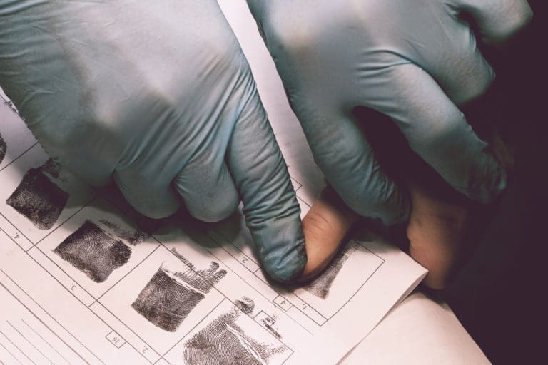 A person in a blue glove is holding a piece of paper.