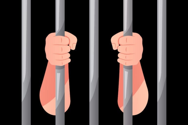 A pair of hands in a jail cell.