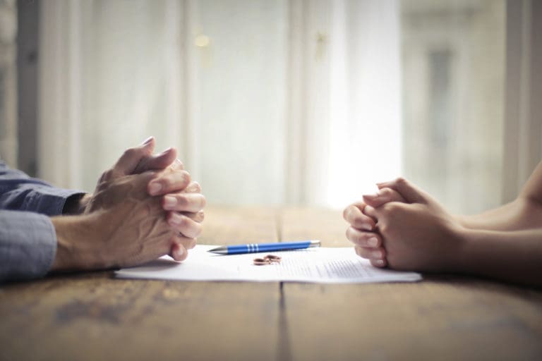 Two people sitting at a table and holding hands.