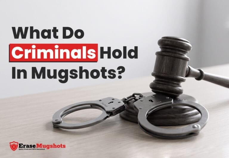 A judge's gavel and handcuffs rest on a table, accompanied by the text "What Do Criminals Hold in Mugshots?" and the Erase Mugshots logo displayed in the corner.